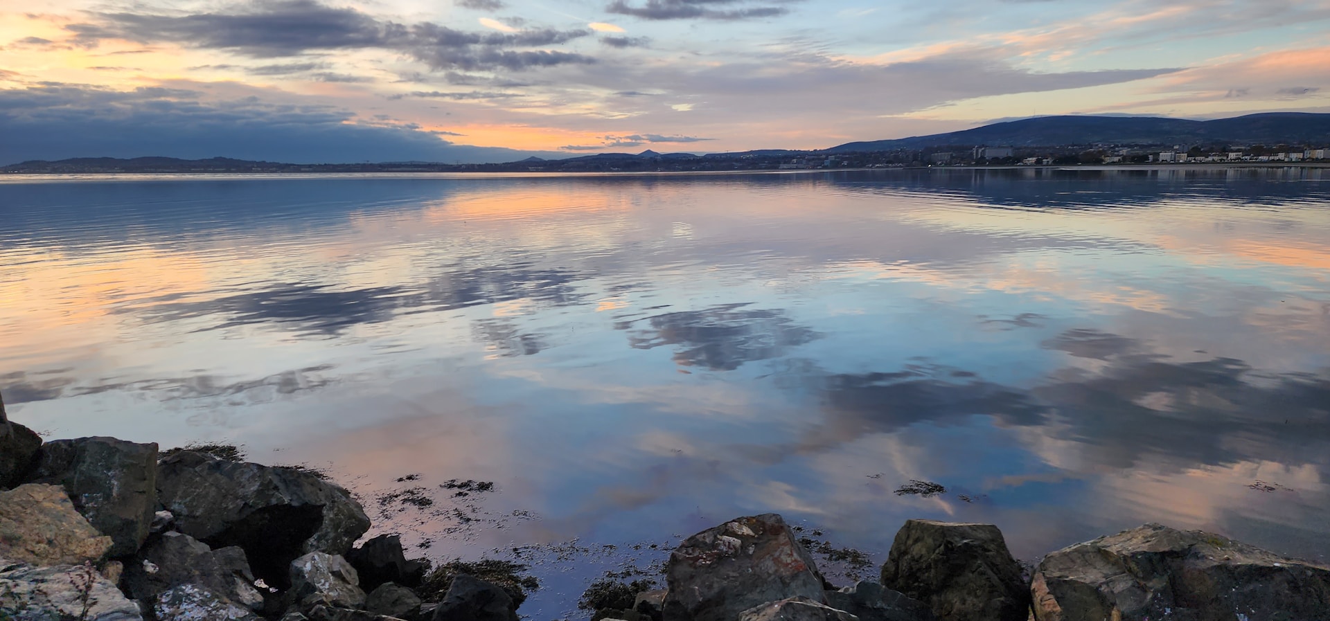 A serene lakeside scene with gentle ripples and distant mountains under a pastel sky, inviting peaceful meditation.