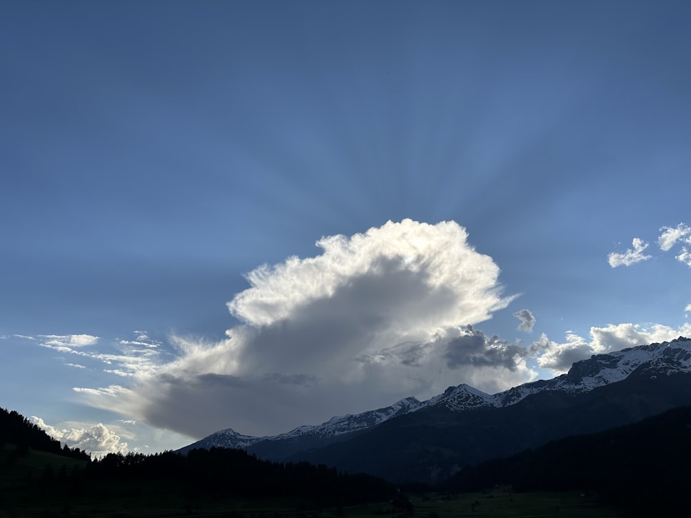 a large cloud in the sky over a mountain range