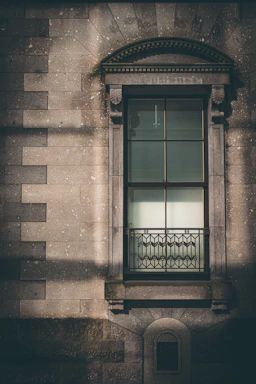 A large, detailed cast stone window sill displayed outdoors on a rustic brick wall, showcasing its texture and craftsmanship.