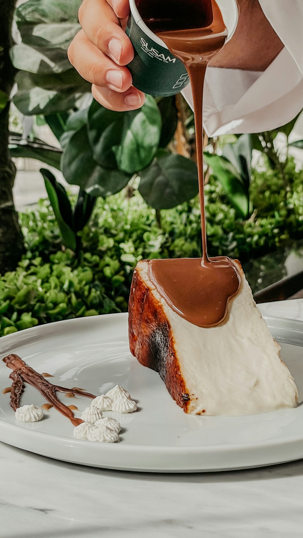 a piece of cake on a plate being drizzled with chocolate