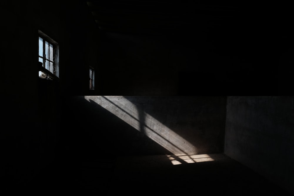 a dark room with two windows and a light coming through the window