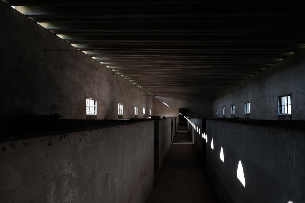un pasillo oscuro con varias ventanas y una pared larga