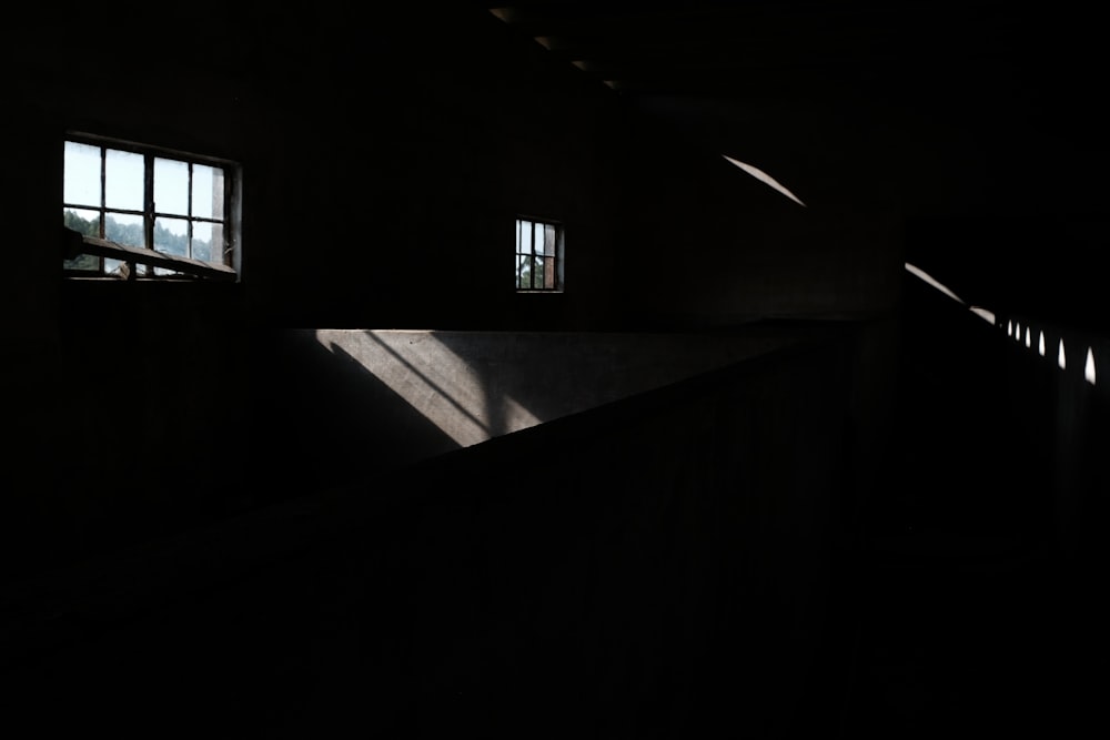 a dark room with three windows and a staircase