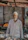An elderly man proudly standing in front of a small local market stall with natural products.