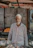 An elderly man proudly standing in front of a small local market stall with natural products.