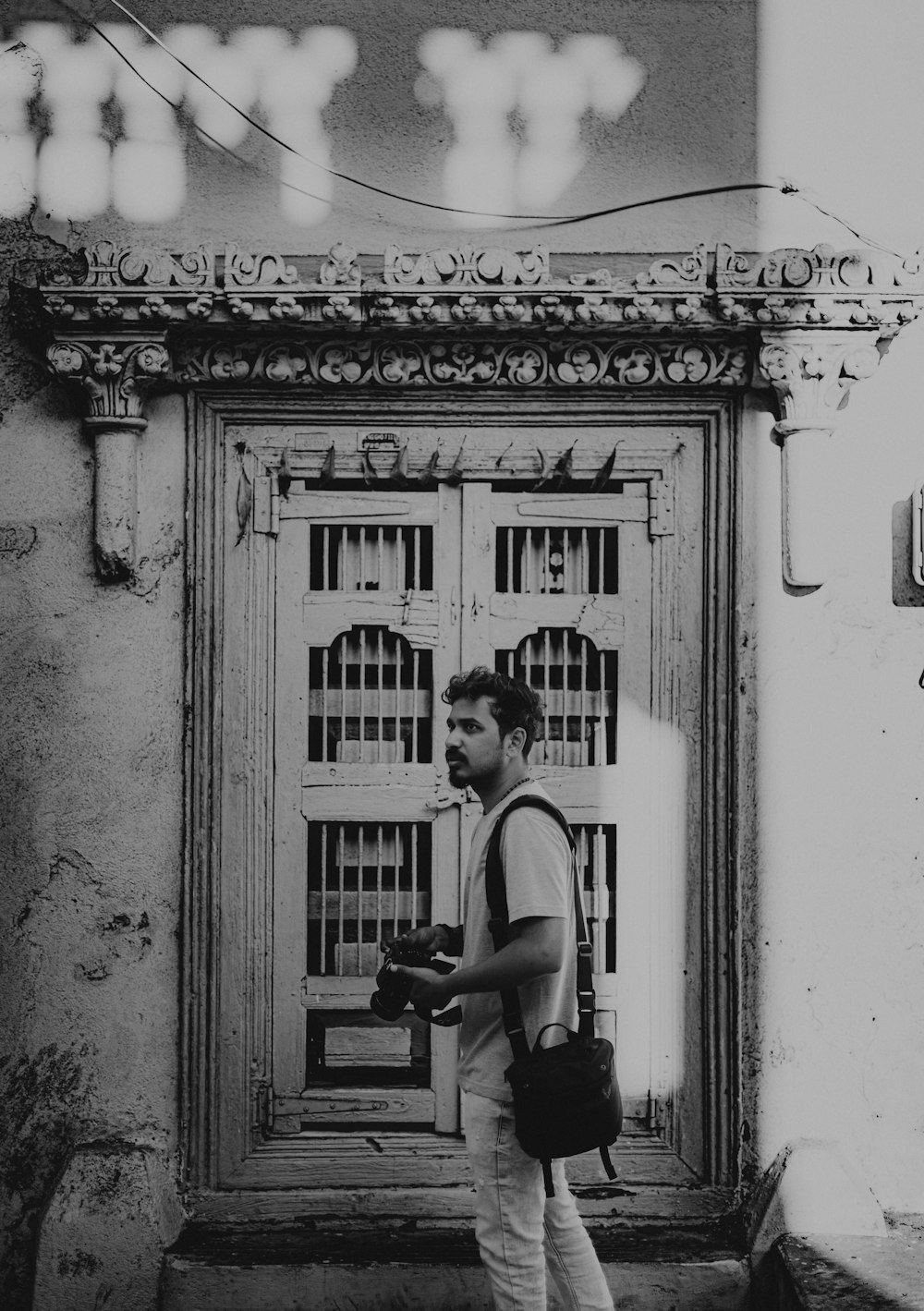 a black and white photo of a man walking in front of a door