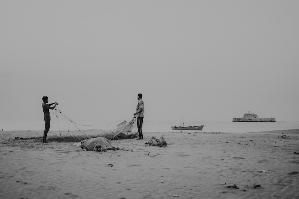 a couple of men standing on top of a sandy beach