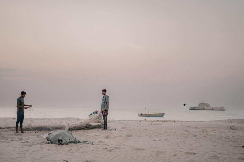 a couple of men standing on top of a sandy beach