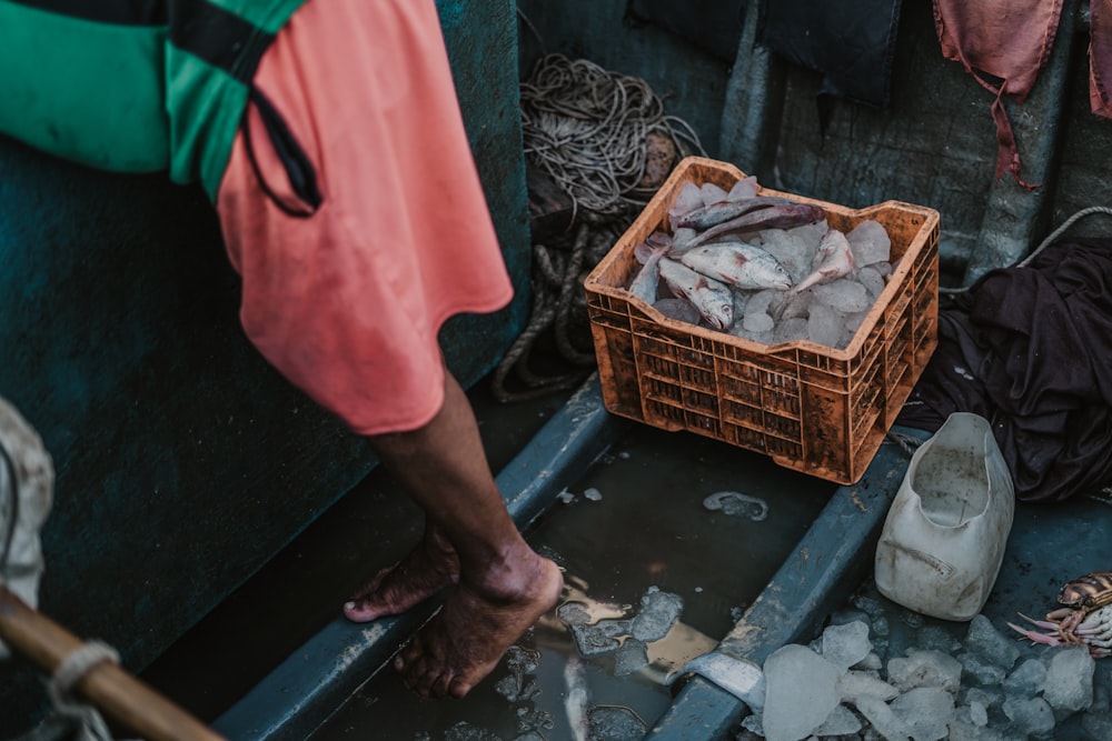 a person standing next to a basket of fish