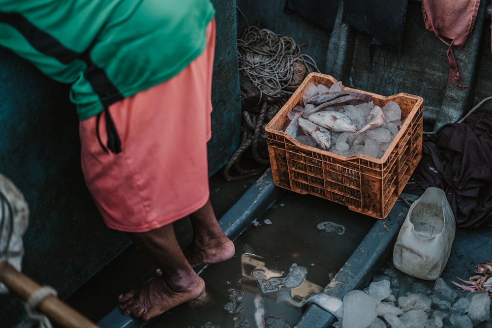 a person standing next to a basket of fish