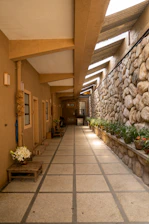 a long hallway with a stone wall and planters