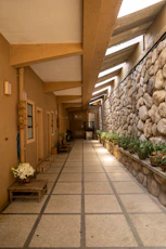 a long hallway with a stone wall and planters
