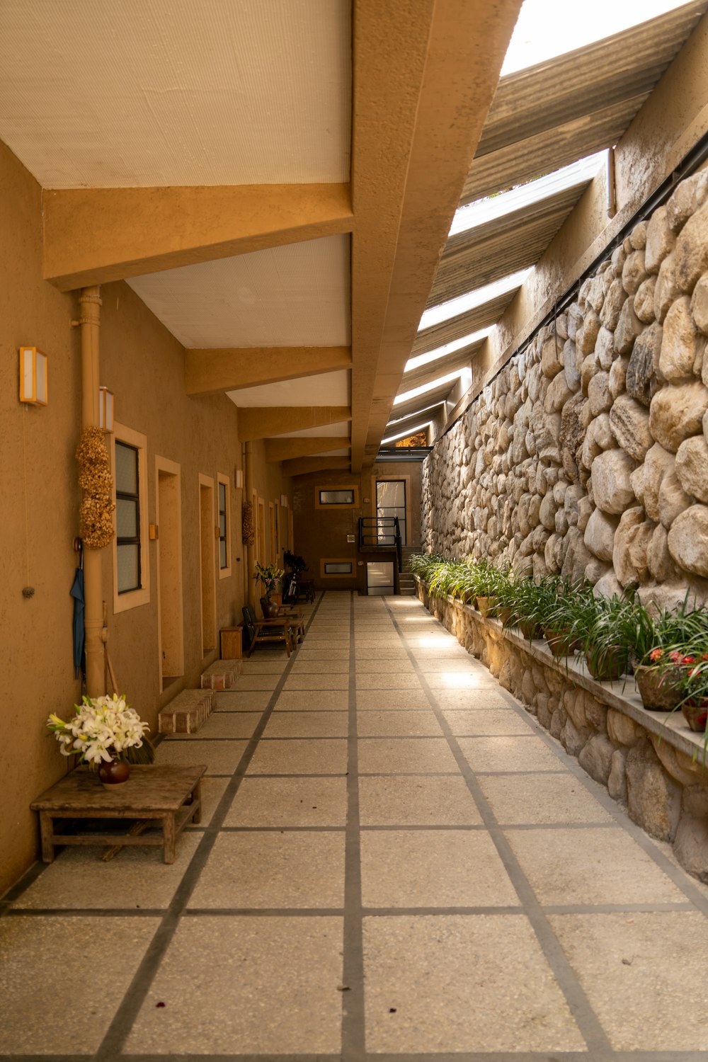 a long hallway with a stone wall and planters