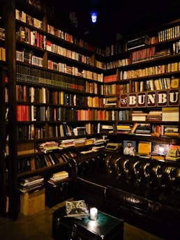 A cozy, festive library corner with warm brown wooden shelves filled with books, glowing orange and red fairy lights, and a magical Harry Potter-inspired atmosphere.