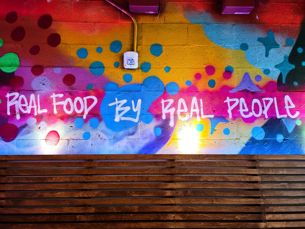 a wooden bench sitting in front of a colorful wall