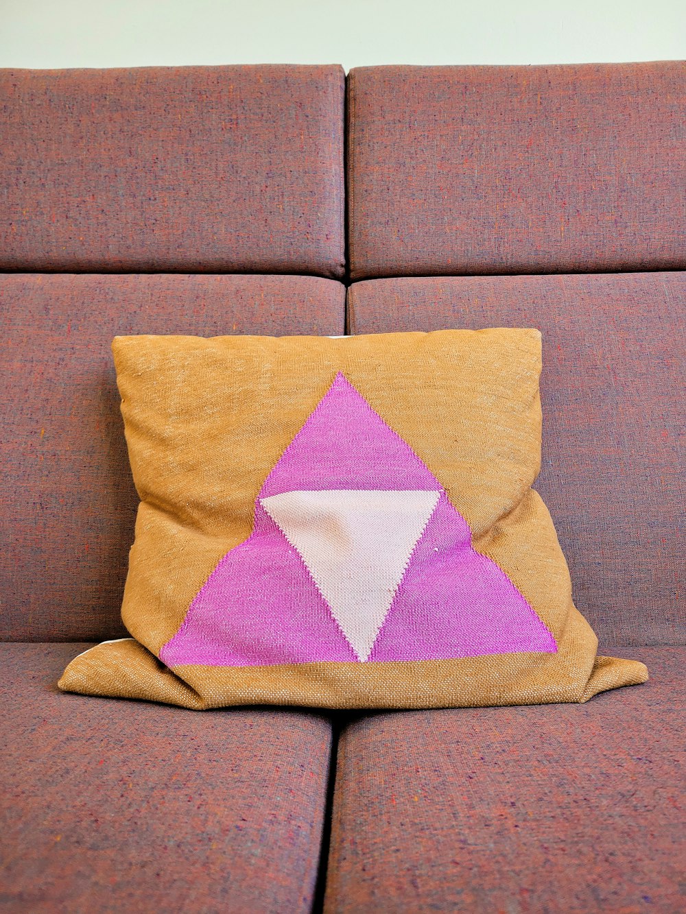 a brown couch with a pink and white pillow on it