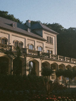 A dignified, historic hostel building bathed in soft morning light, framed by lush greenery.