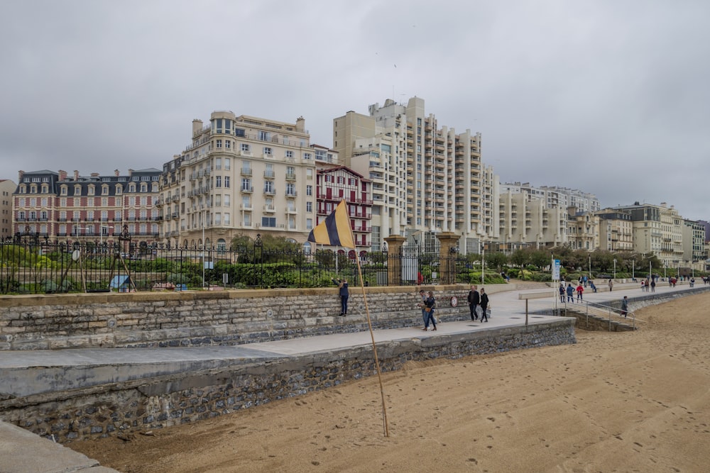 a group of people walking along a beach next to tall buildings