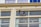 Two workers are suspended on ropes cleaning the windows of a tall building. They are equipped with safety gear, including helmets and harnesses, and are positioned near large glass windows.
