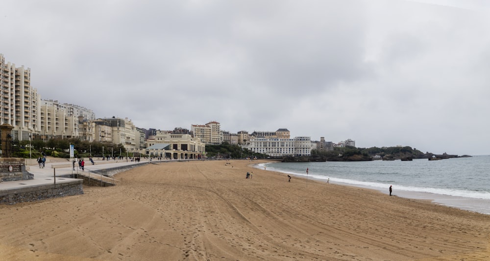 a sandy beach next to the ocean with buildings in the background