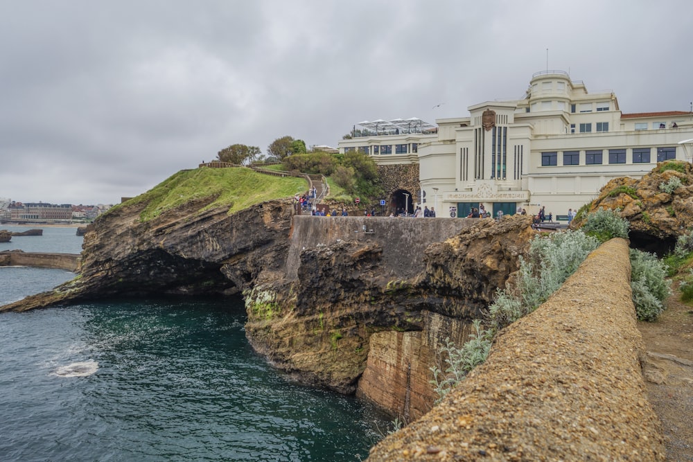 a group of people standing on top of a cliff next to the ocean