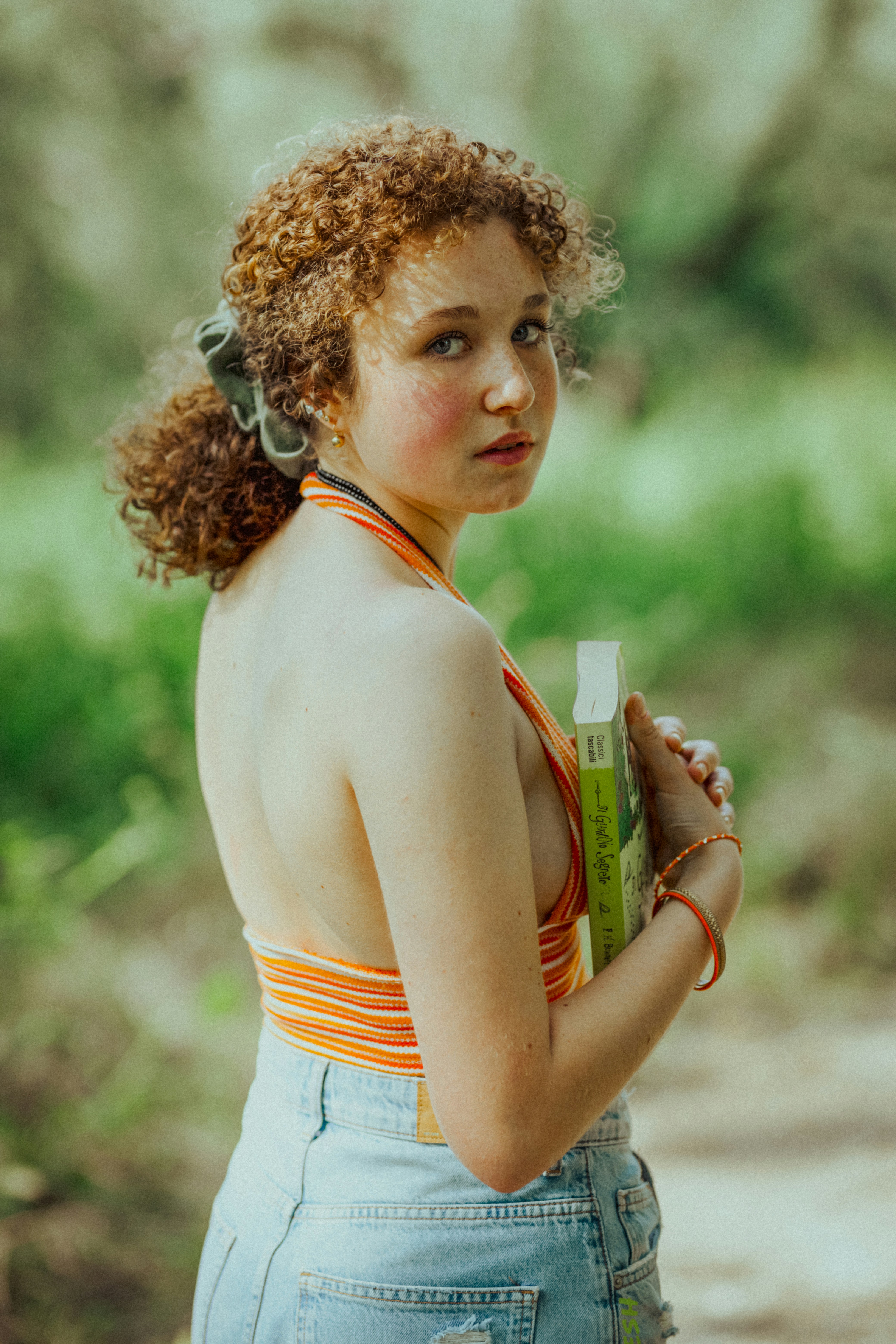a woman in overalls holding a bottle of sunscreen