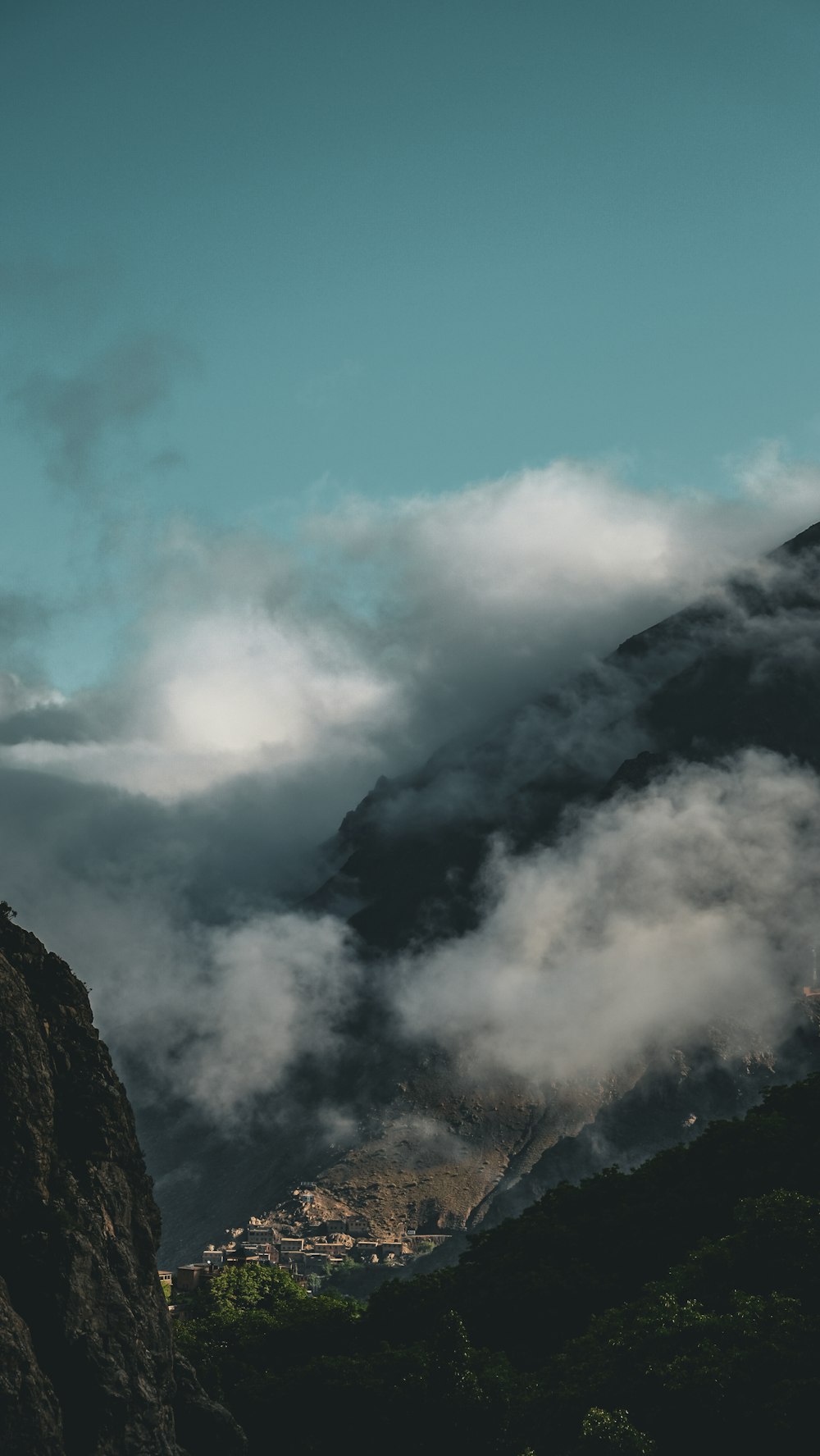 a mountain covered in clouds with a town in the distance