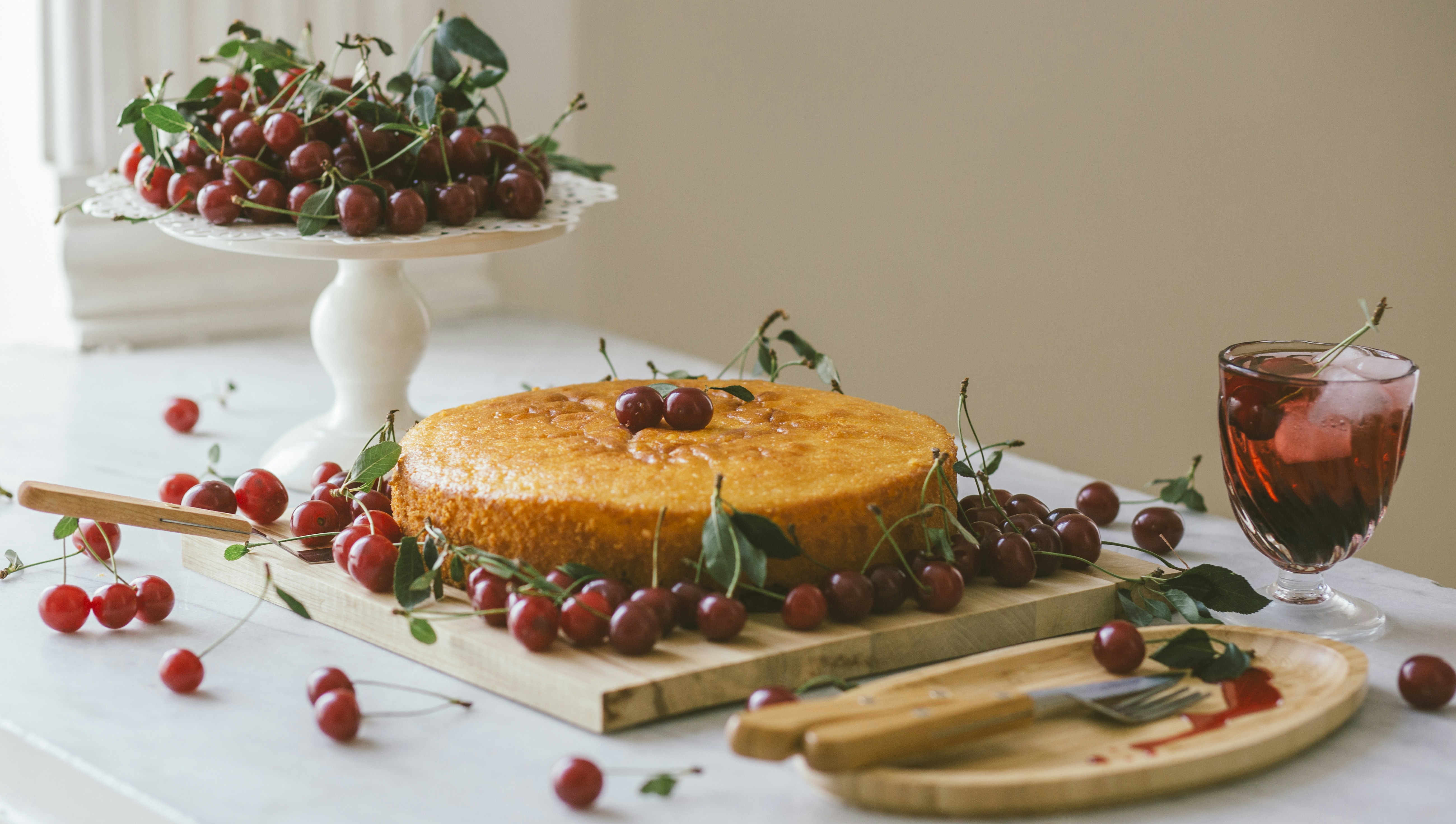 Homemade cherry cake, delicious fruit cake. Summer fruit dessert and a cold drink and bowl with fresh cherries.Healthy nutrition, vegan dessert, Selective focus. Header.