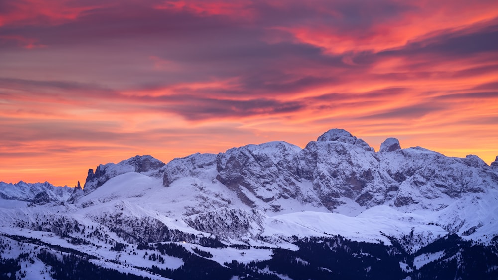 a mountain range covered in snow at sunset