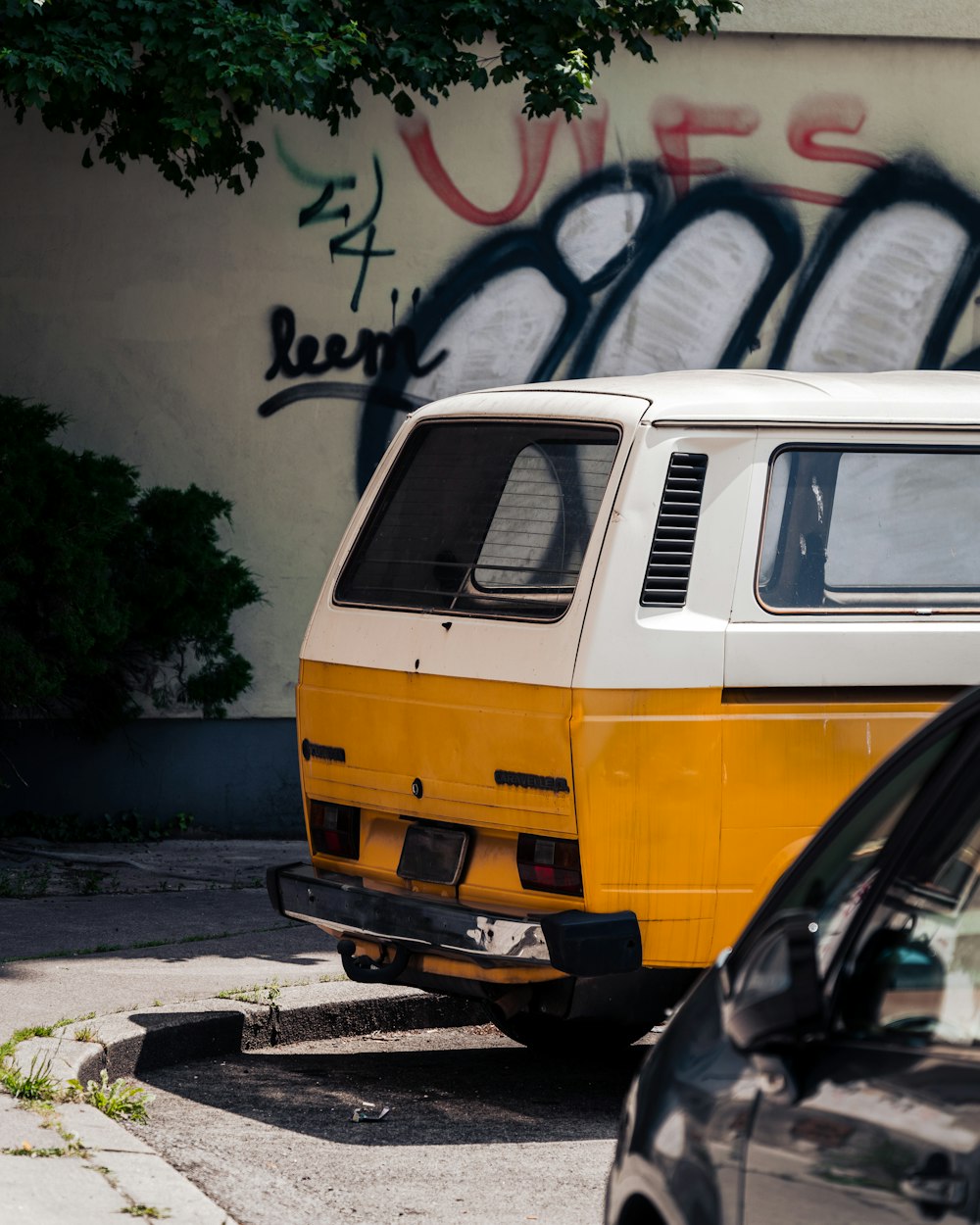 a yellow and white van parked next to a black car