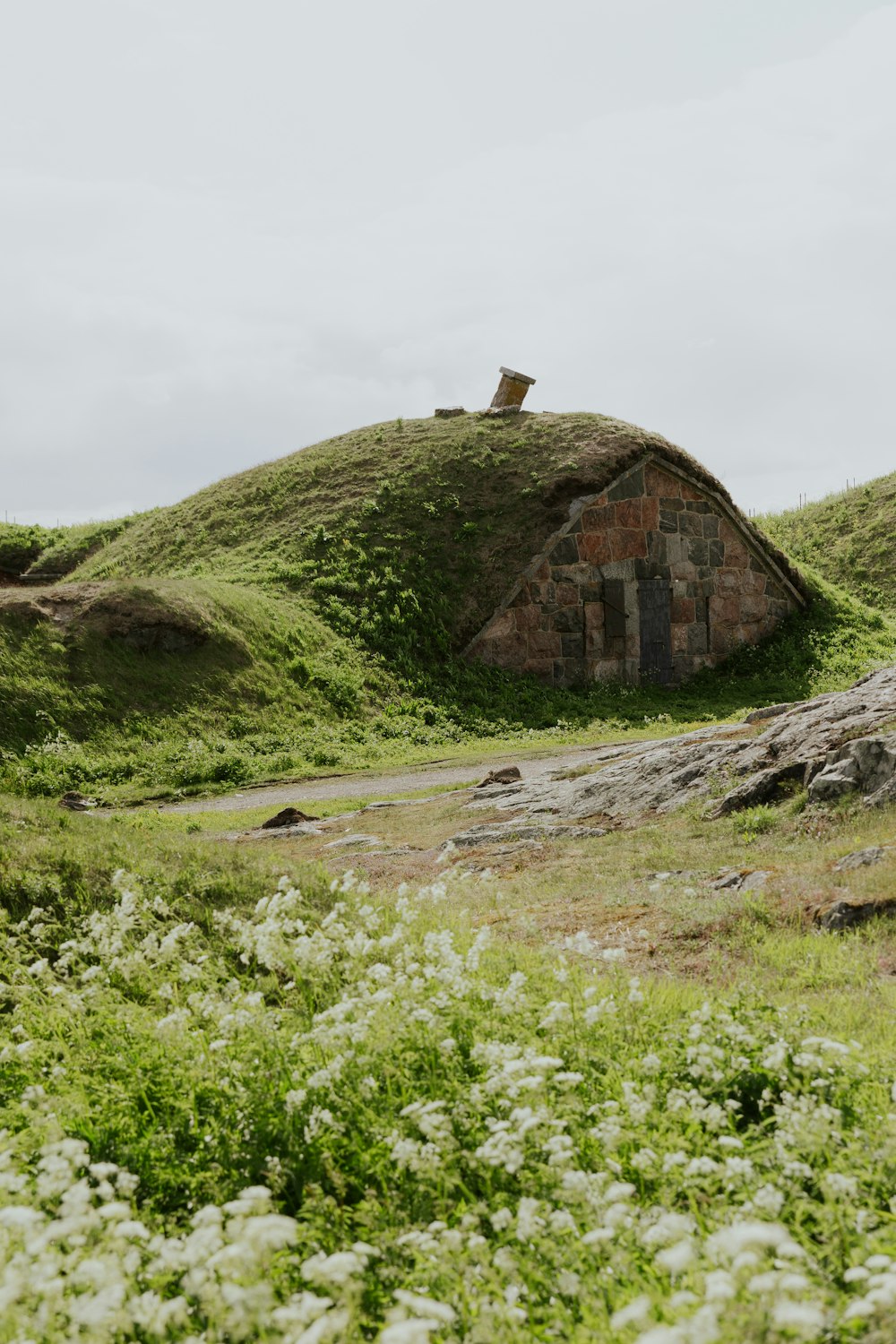 a grassy field with a small house on top of it