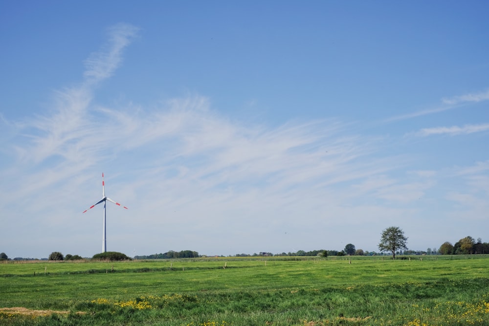 a green field with a windmill in the distance