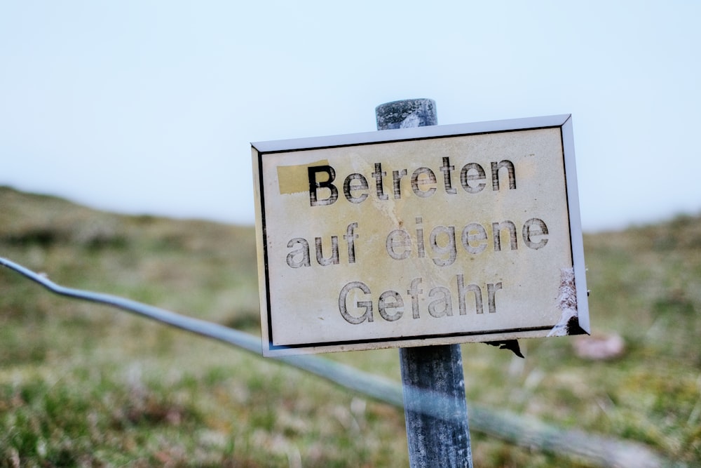 a sign that is on a pole in the grass