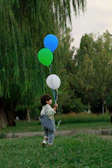 A joyful child running with colorful balloons in a park