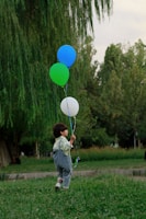 A candid shot of a child named Allen playing joyfully in a park with colorful balloons.
