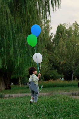 A joyful child running with colorful balloons in a park