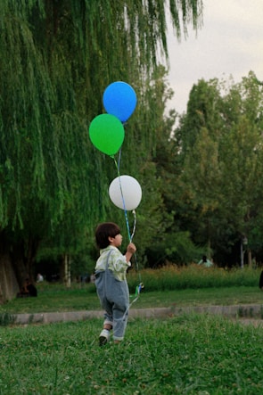 A candid shot of a child named Allen playing joyfully in a park with colorful balloons.
