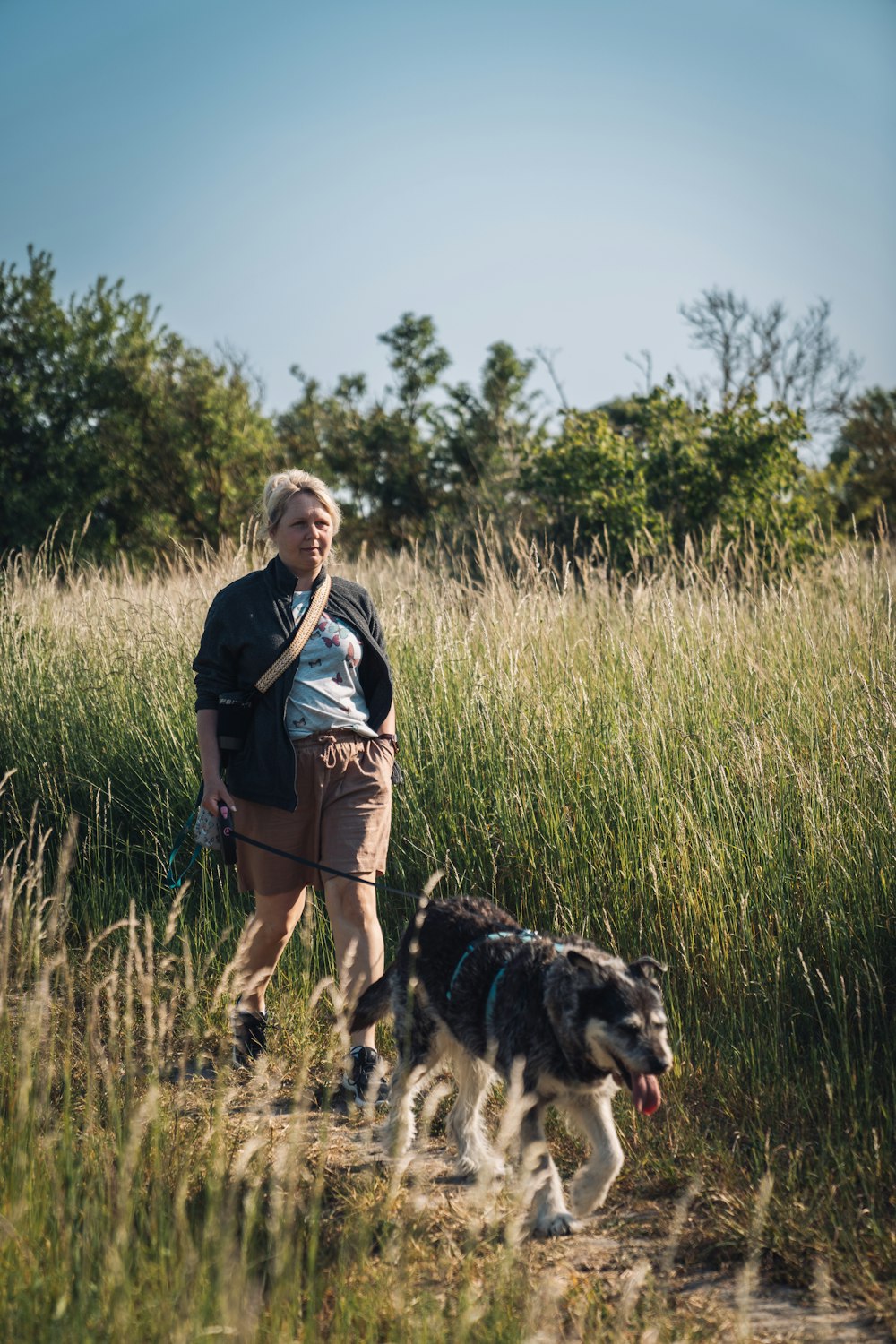 a woman walking a dog in a field