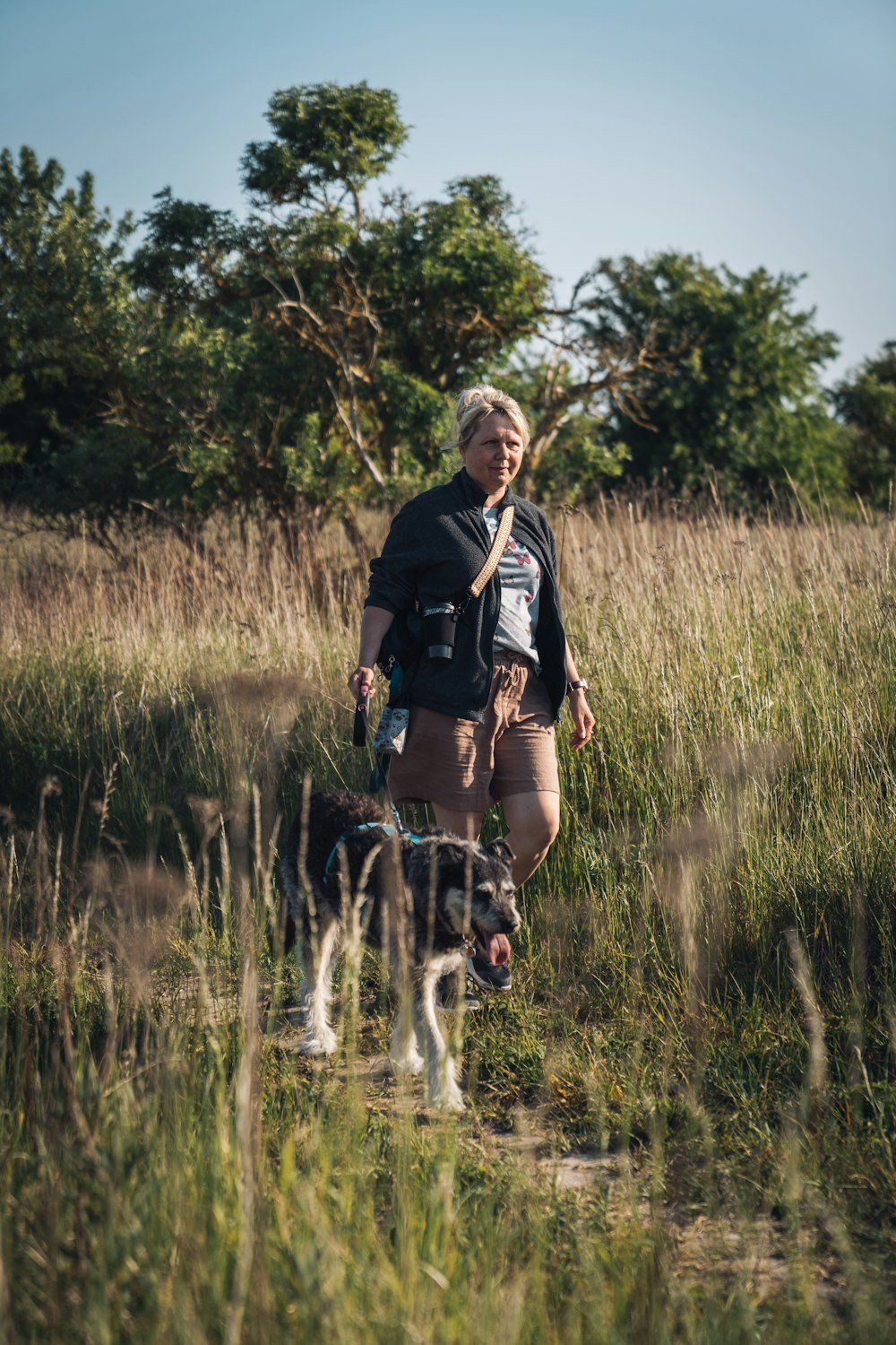 a woman walking a dog in a field