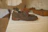 Close-up of a stylish brown leather shoe resting on a wooden bench.