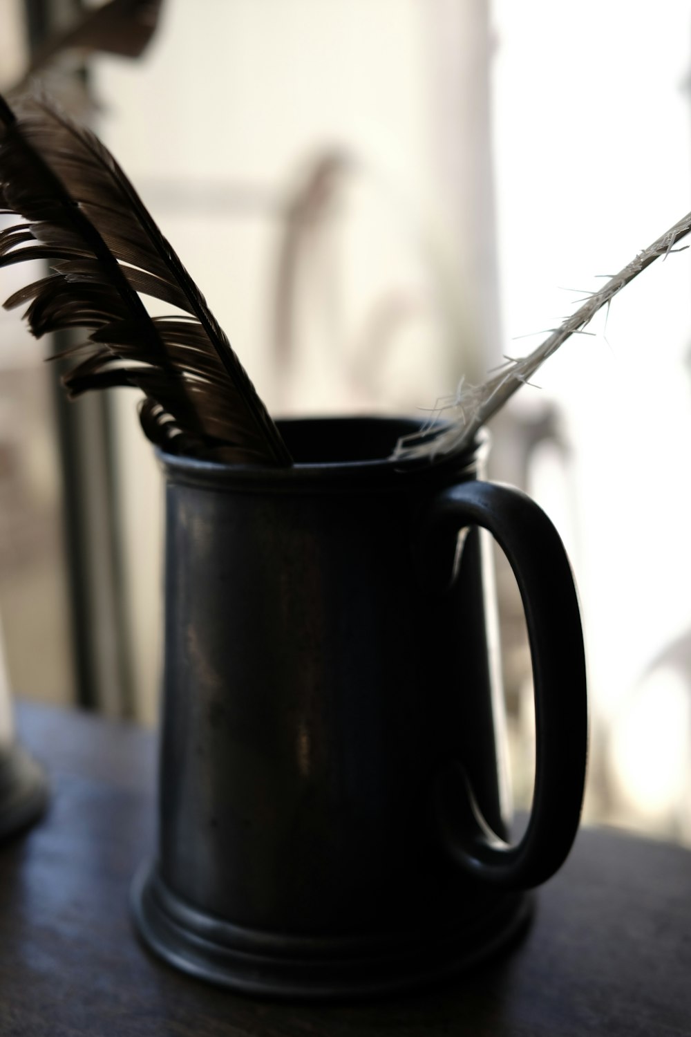 a black mug with a feather in it