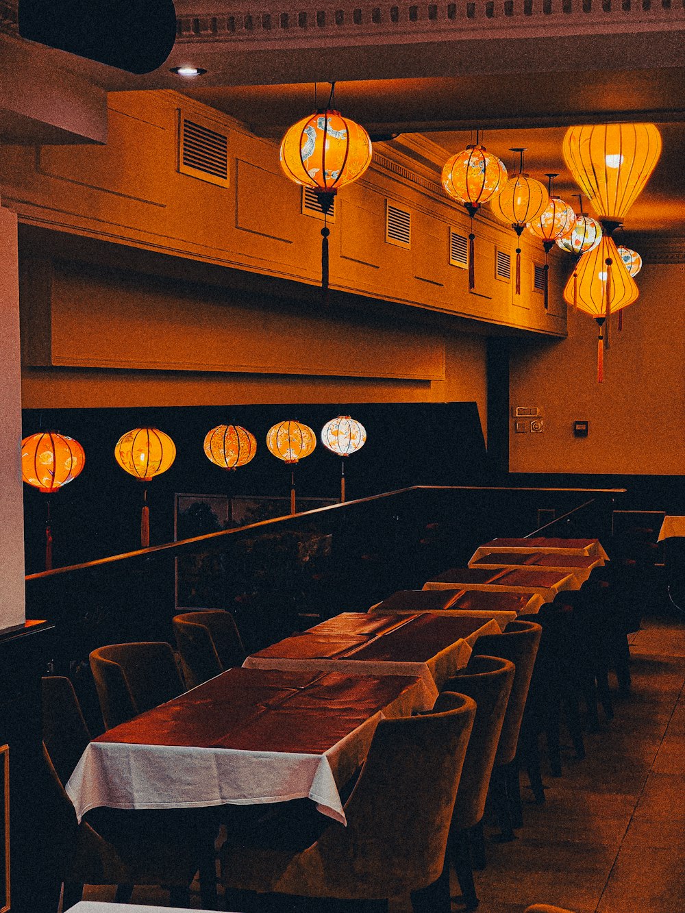 a restaurant with a long table and lanterns hanging from the ceiling