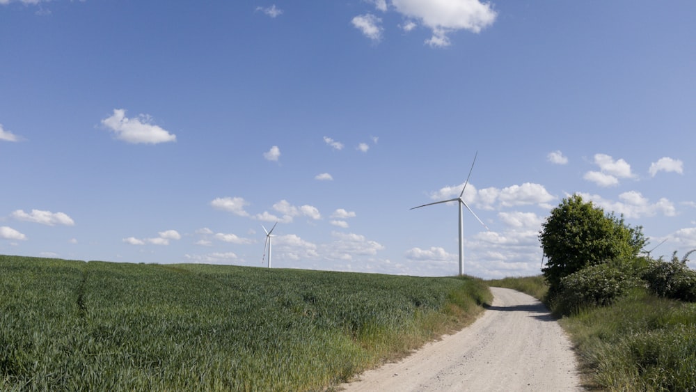 a dirt road with wind turbines in the distance