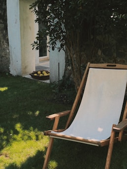 a lawn chair sitting in the grass next to a tree