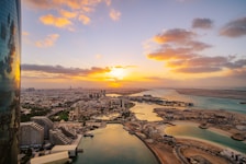 the sun is setting over a city and a body of water