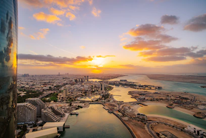 the sun is setting over a city and a body of water