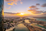 the sun is setting over a city and a body of water