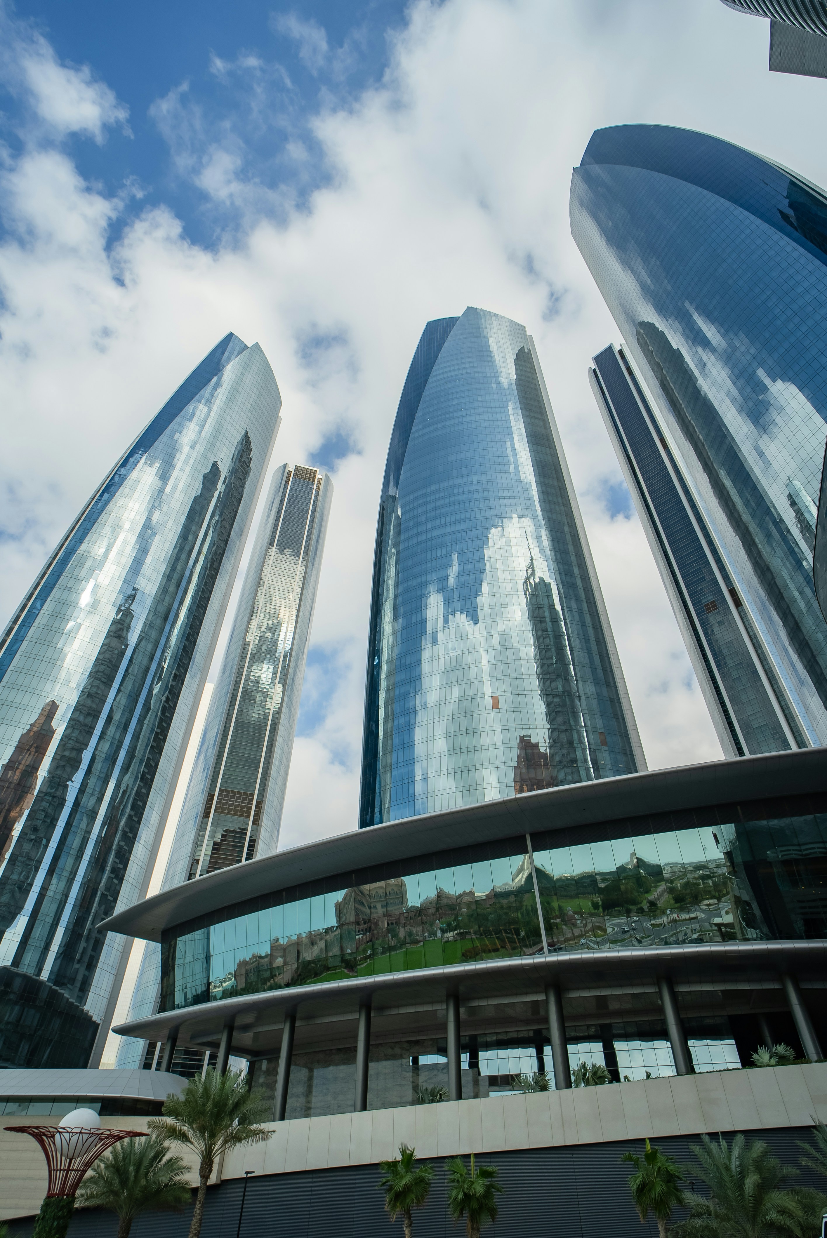 Modern commercial office building exterior with glass facade reflecting blue sky in bright daylight