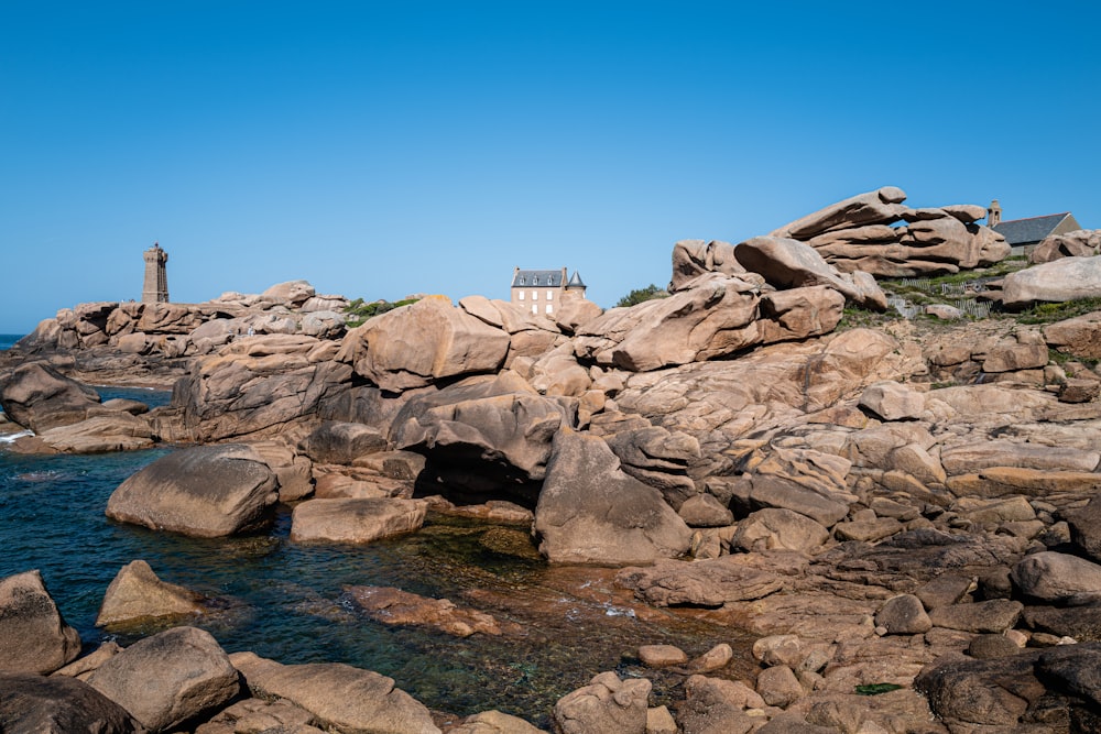 a rocky shore with a lighthouse in the distance