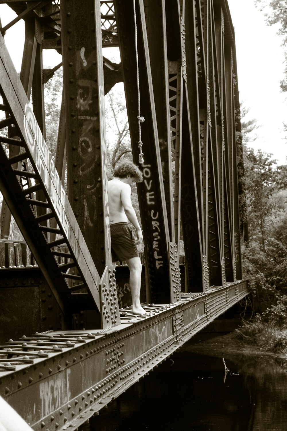a shirtless man standing on a bridge next to a body of water